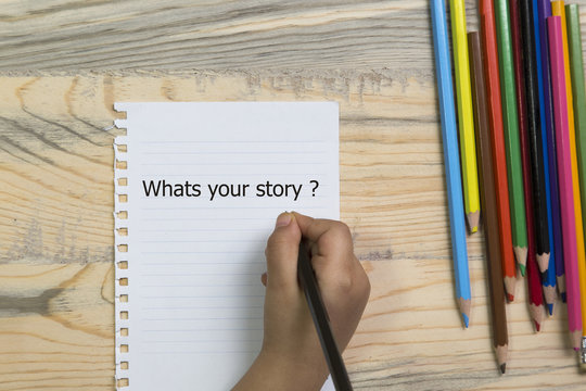 hand writing what's your story.wood table colored crayons