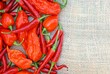 An assortment of thai dragons, bhut jolokia, scotch bonnet peppers on a burlap background with room for text