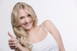 © StudioLaMagica - Junge hübsche blonde Frau zeigt Daumen hoch