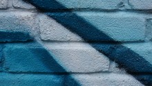 Blue White Painted Wall With Graffiti Painting On Brick Structure Giving An Abstract Background Pattern.