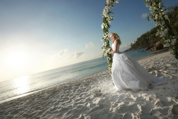 Gorgeous bride smiling, standing under wedding arch during suns