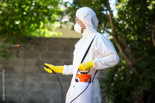 Fotografía Side view of worker using pesticide in back yard