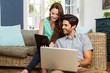 © WavebreakmediaMicro - Couple using digital tablet and laptop in living room