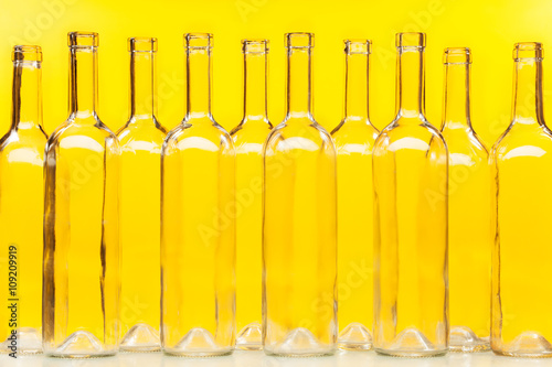 Fototapeta Empty transparent glass bottles over yellow wall