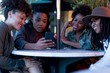 © Connect Images - Group of female friends sitting at table, looking at smartphone, outdoors