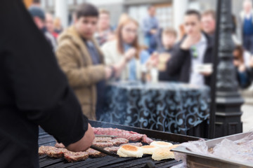 Wall Mural - Chef making beef burgers outdoor on open kitchen international food festival event. Street food ready to serve on a food stall.