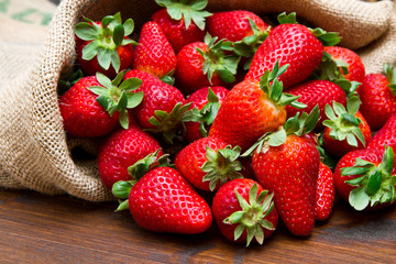 fresh strawberry in burlap sack on wood