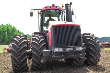 Wall Mural - Modern tech red tractor plowing a green agricultural field in spring on the farm. Harvester sowing wheat.