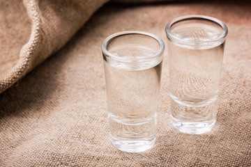 Vodka glasses on retro linen fabric texture. 