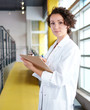© AYAimages - Portrait of a female doctor holding her patient chart in bright modern hospital