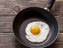 Fried Sunny Side Up Eggs On A Pan On A Brown Oak Old Wooden Board