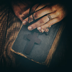 Poster - closeup of hands holding vintage cross on Bible