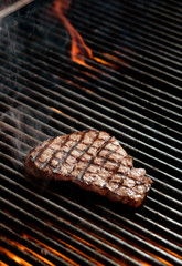 beef steak cooking over flaming grill