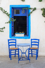 Table And Chairs In Front Of A Greek House With Window