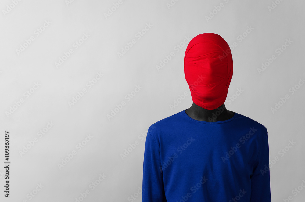 Surrealism Theme: man in a blue jacket with a red cloth tied around his head is in the corner on a gray background - obrazy, fototapety, plakaty 