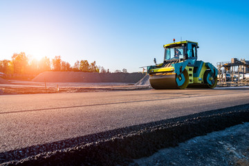 Sunset above the road rollers working on the construction site