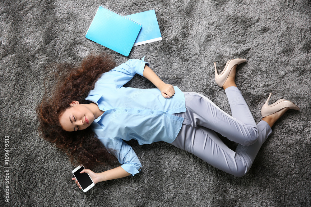 Young woman with a smartphone relaxing on the floor