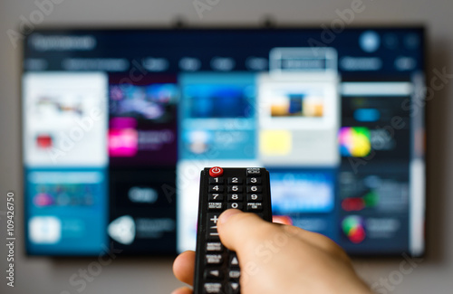 Fotomural Male hand holding TV remote control.
