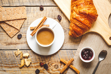 Breakfast with coffee, crackers and croissants on wooden table