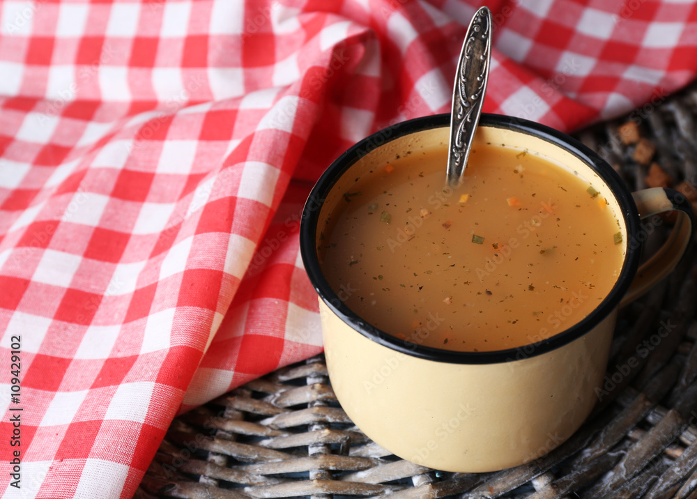 Mug of soup on wicker mat on a table closeup