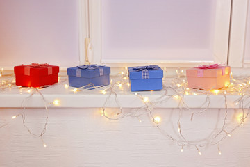 Canvas Print - Colourful gift boxes and glowing lights are on window board, close up