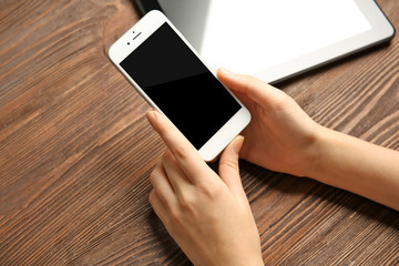 Canvas Print - A tablet and female hands using mobile phone, on the wooden background