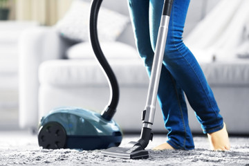 Wall Mural - Woman cleaning the carpet with vacuum cleaner in the living room