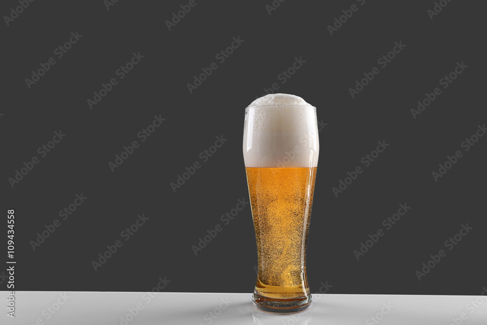 Glass of lager beer on grey background