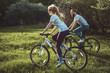 Beautiful young girl and man walking with a bike ride on the green grass. The concept of active rest