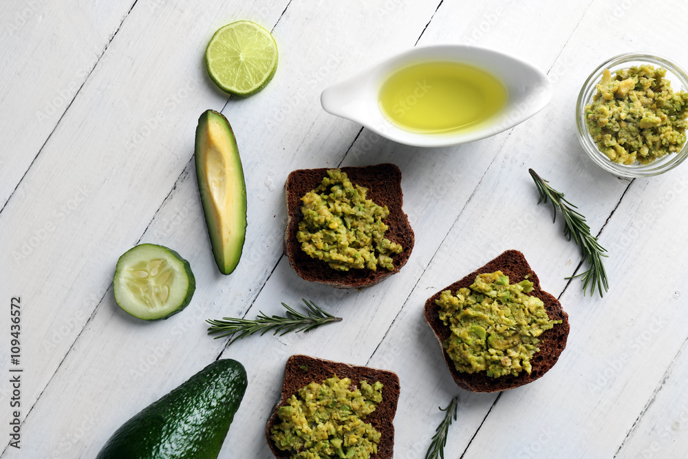 Avocado sandwiches with vegetables on wooden background