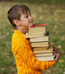 Wall Mural - little happy boy carrying stack of books