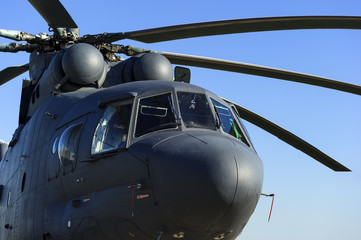 Military heavy helicopter, army air means of transport, air force, aviation and aerospace industry, grey big copter with rotor in sunny evening, blue sky on background 