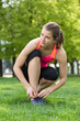 © antgor - Young sporty woman tying shoelaces outdoor on grass