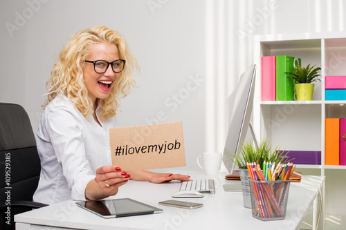Fotografie, Obraz Woman in office showing "I love my job" cardboard