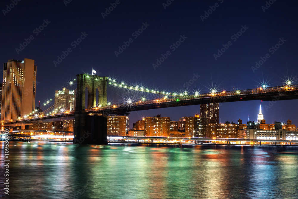 Beautiful New York City view of the Brooklyn Bridge looking towards Manhattan at night - obrazy, fototapety, plakaty 