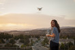 © Image Source - Female commercial operator flying drone above housing development, looking over shoulder at camera, Santa Clarita, California, USA