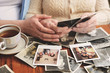 © Image Source - Senior woman and granddaughter sitting at table, looking through old photographs, mid section
