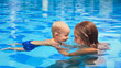 © Tropical studio - Happy little sports man with mother - active baby swim with fun in woman hands in swimming pool. Swimming people, family lifestyle and summer children water activity and swimming lesson with parents.