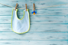 Baby Bib And Pacifier Hanging On A Clothesline On Wooden Background