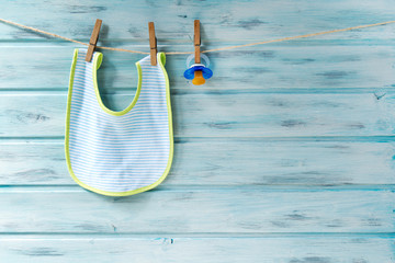 Wall Mural - Baby bib and pacifier hanging on a clothesline on wooden background