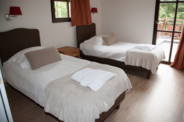 A bedroom in a new house with two single beds and large window's.