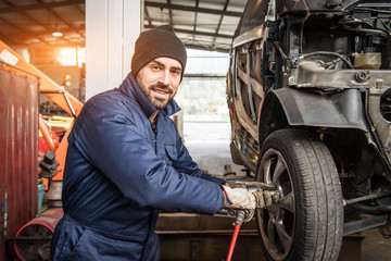 Mechanic changing car wheel at service.