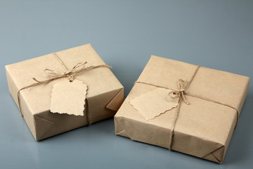 two parcels tied with rope and tag on gray wooden background