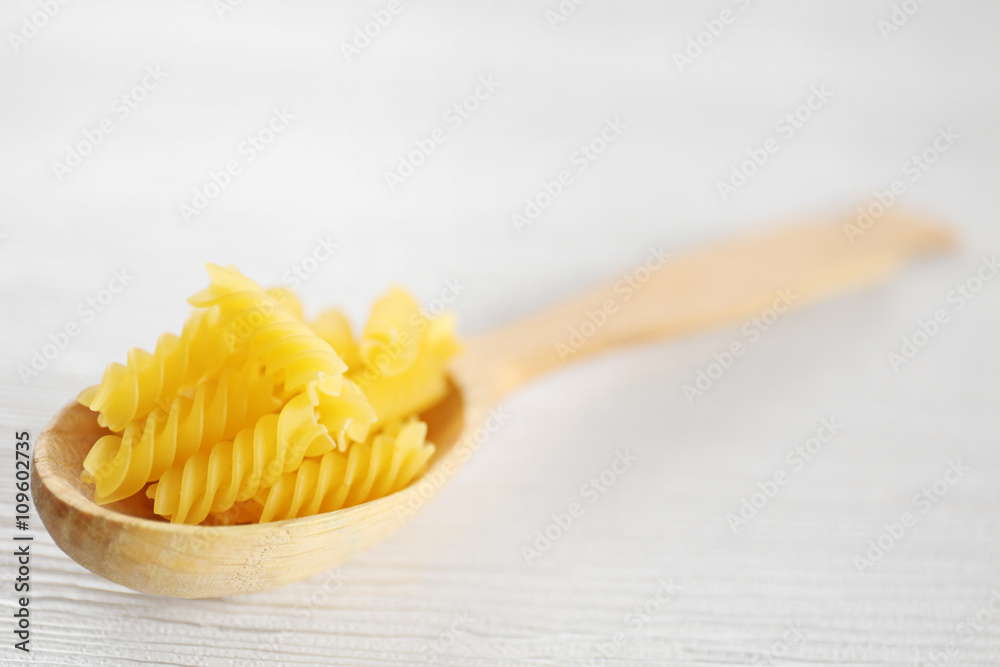 Fresh uncooked pasta in wooden spoon on table closeup