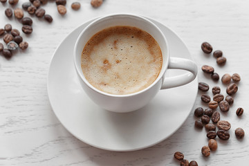 Canvas Print - Cup of coffee and coffee beans on light wooden background