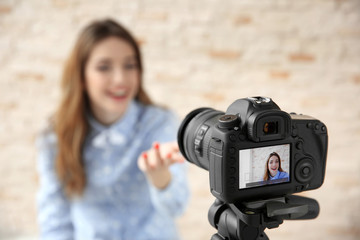 Young female blogger with laptop on camera screen