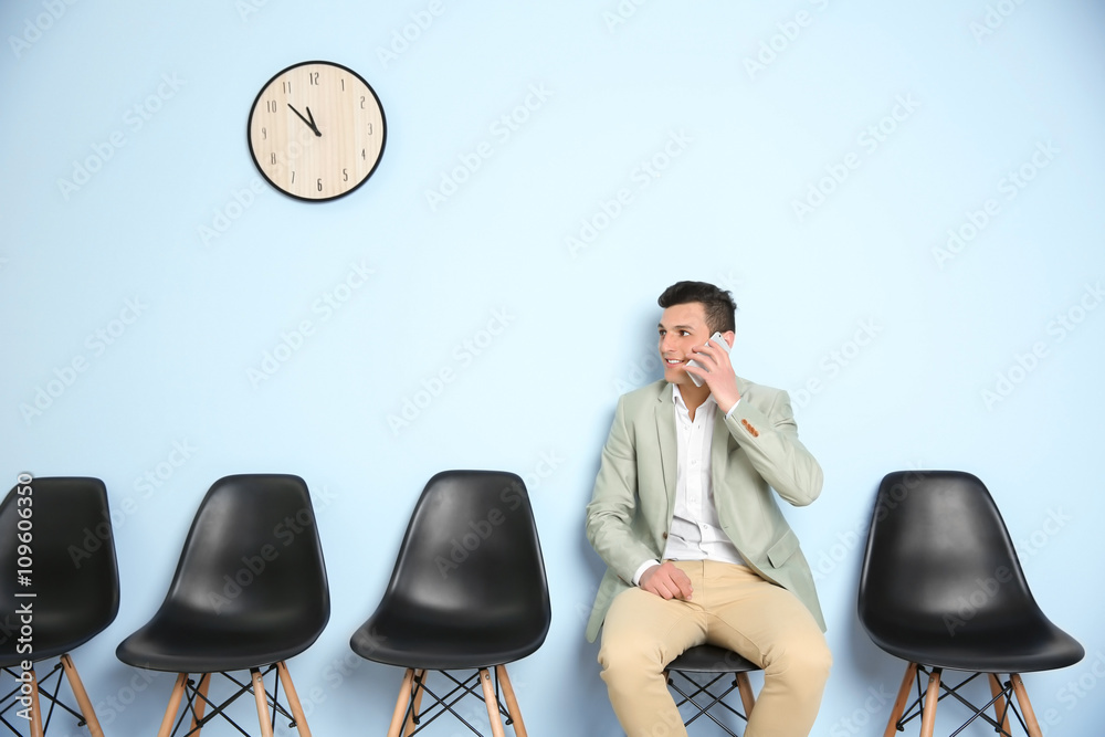 Young man in suit talking on phone and waiting for job interview