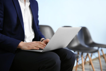 Poster - Young man in suit sitting on chair with laptop closeup