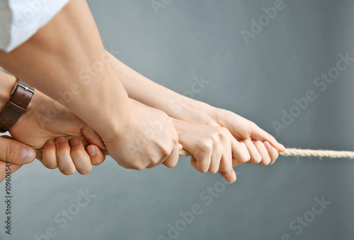 Fotografía People hands pulling rope for playing tug of war on grey background