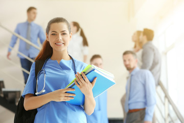 Poster - Smiling young female student with backpack and books, indoors